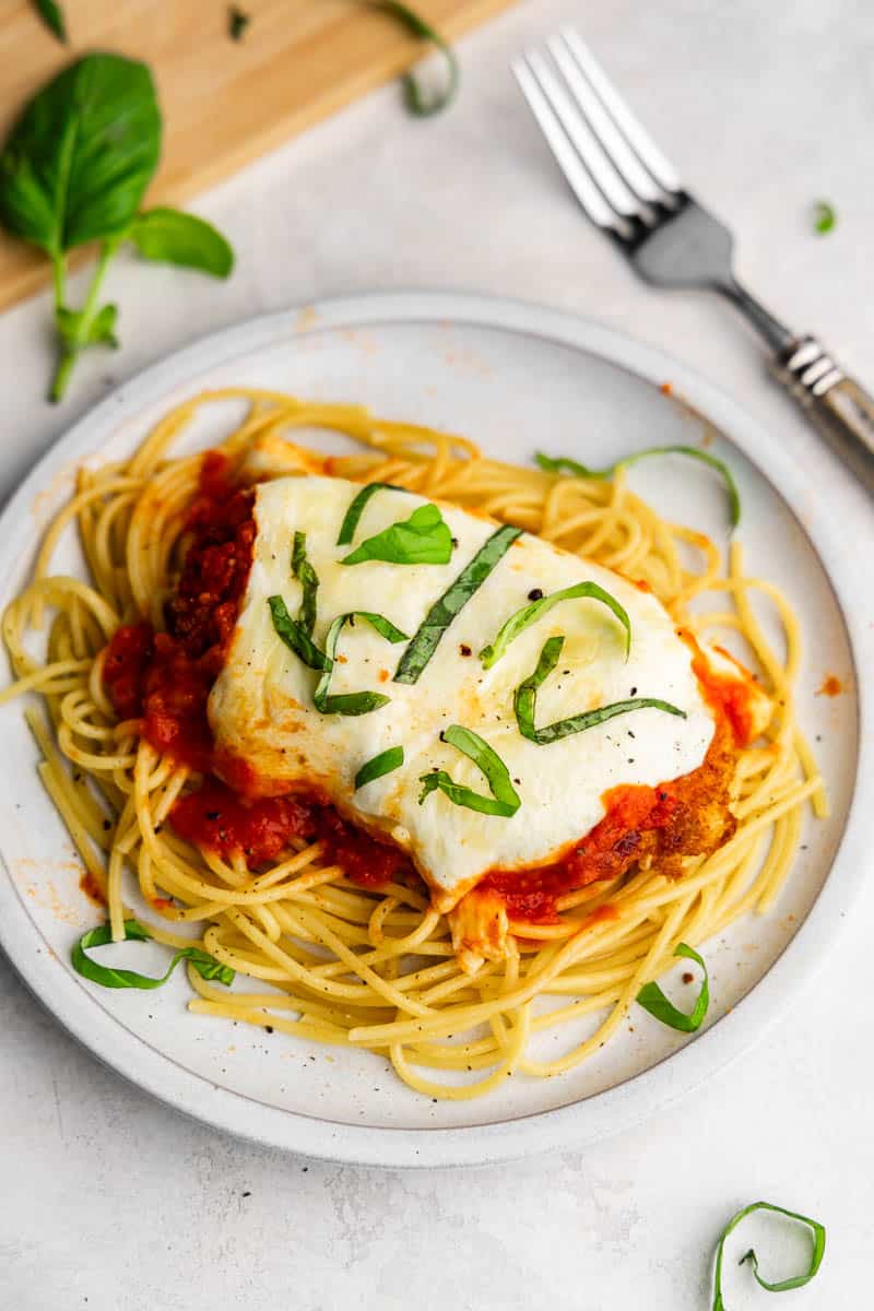 An overhead view of a plate of chicken parmesan ready to eat.