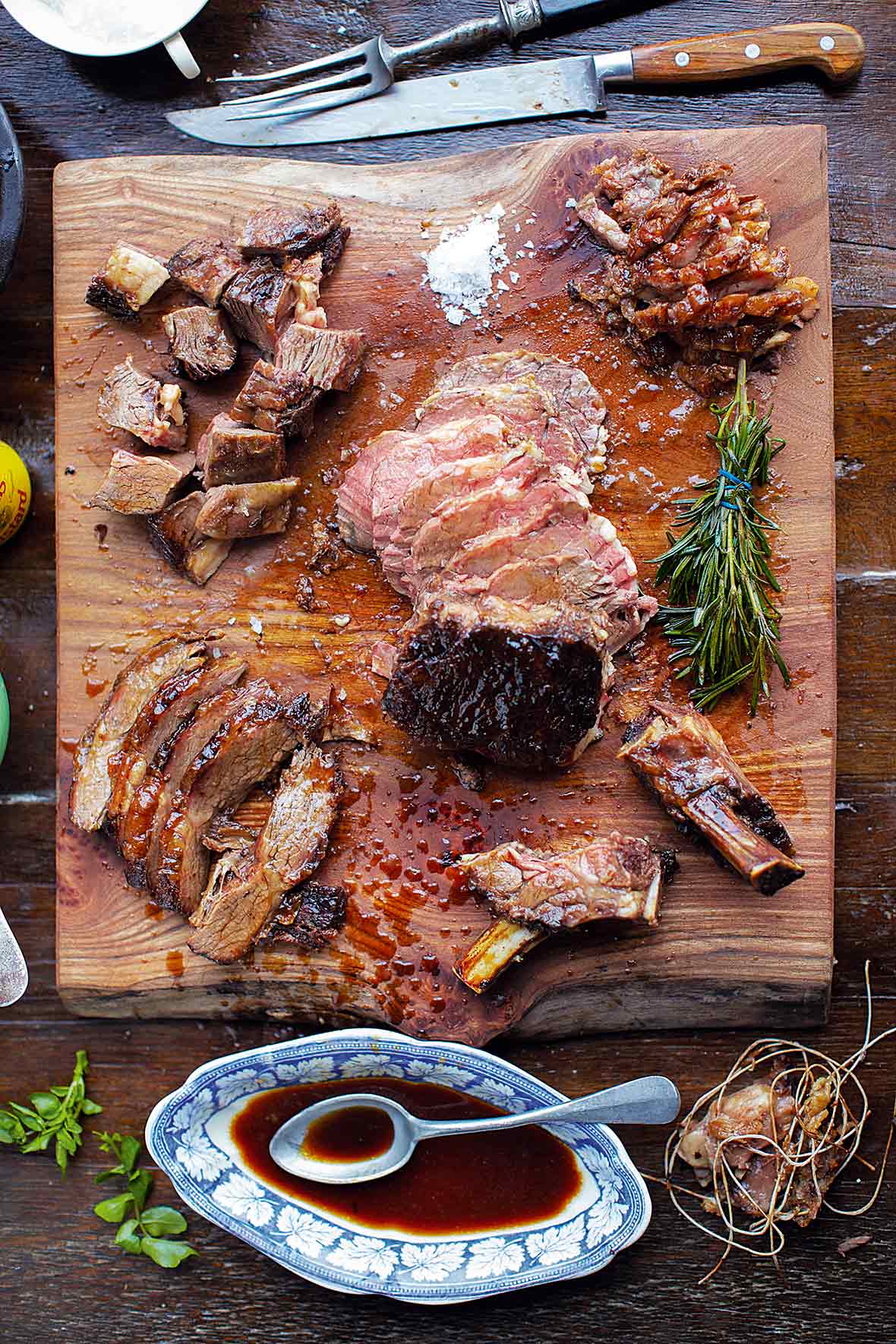 A medium-rare rib roast deboned and sliced into pieces on top of a wooden cutting board